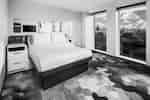 Modern guest room with a bed, large windows, and purple patterned carpet.
