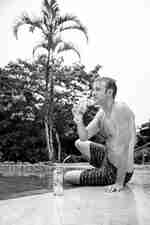 Seorang pria menyeruput koktail tepi kolam di Royal Palm Galapagos, Curio Collection by Hilton