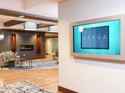 Lobby With Wall Mounted TV and View of Soft Seating Around Fireplace in Lounge Area With View of Front Desk