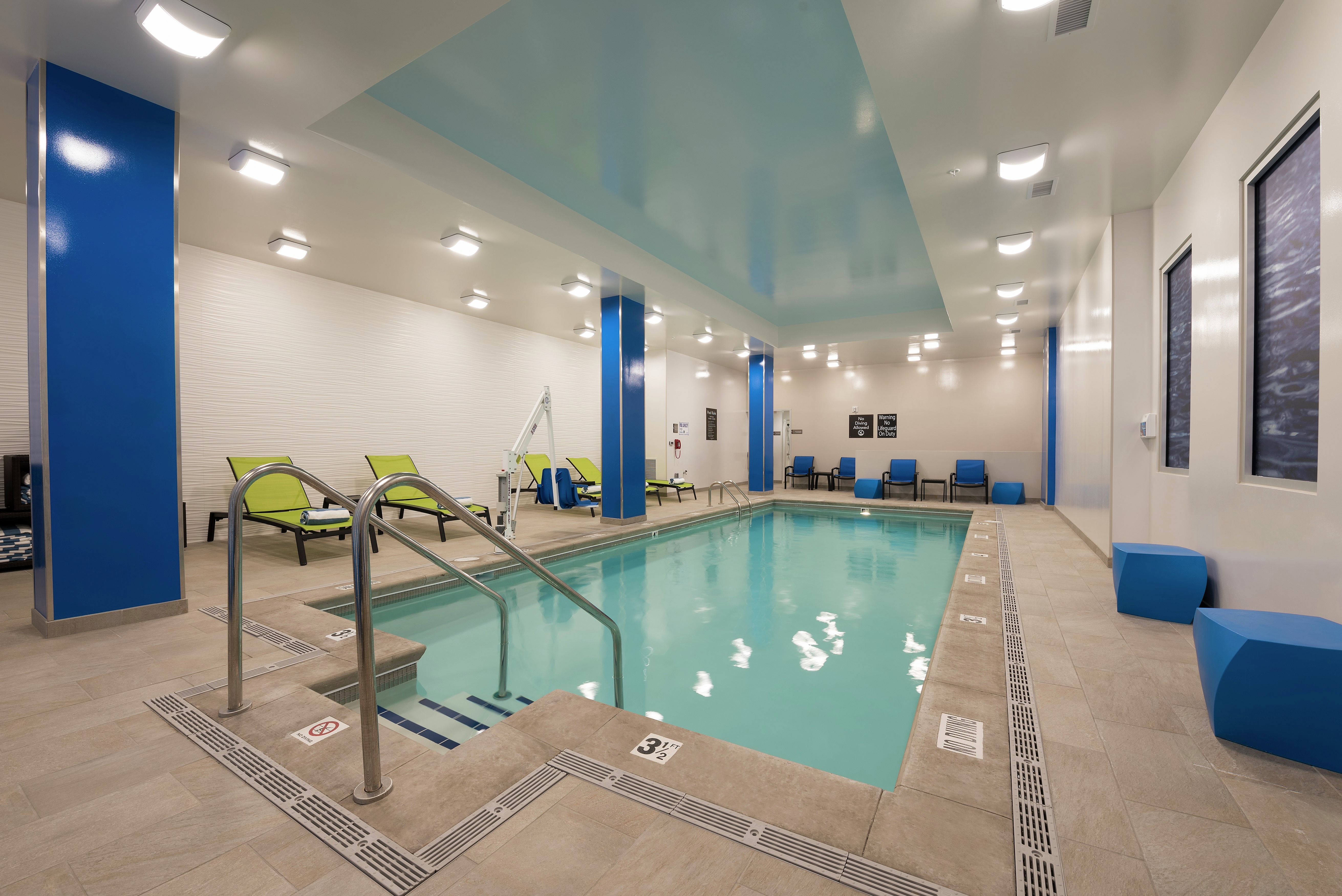 Indoor Pool and With Green Loungers, Blue Chairs, and Windows