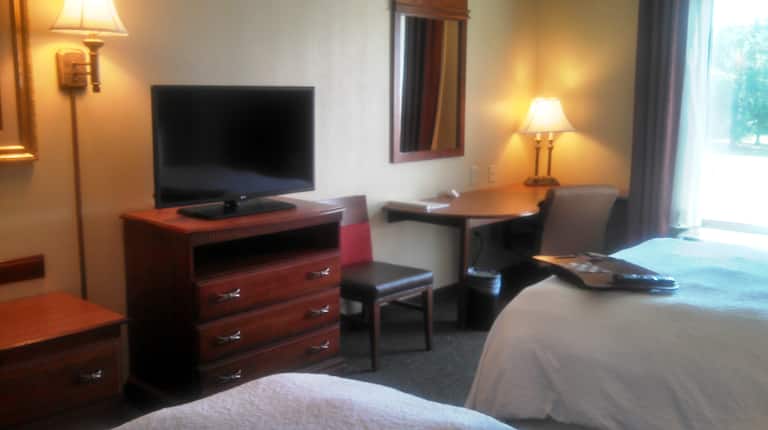 2 beds in room with tv and desk