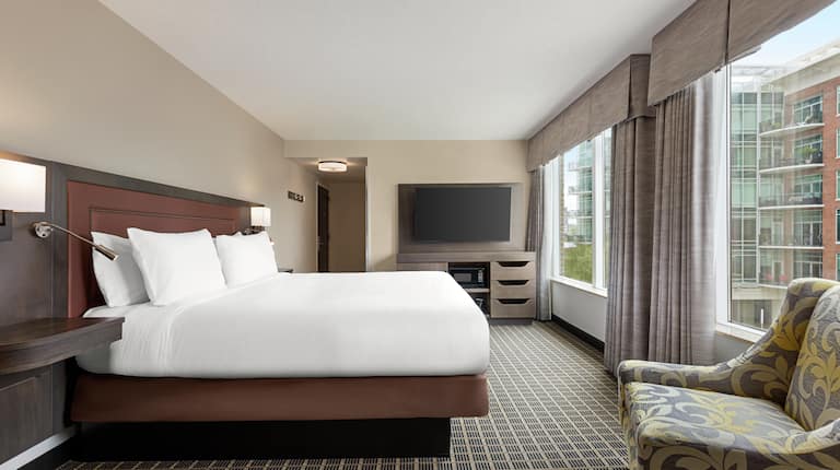 Spacious guestroom featuring comfortable king bed, TV, and beautiful city view.
