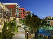 Stunning riverside hotel featuring walking path and glowing city lights.