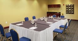 Water Pitchers, Drinking Glasses, Note Pads, and Blue Chairs at Tables in Meeting Space