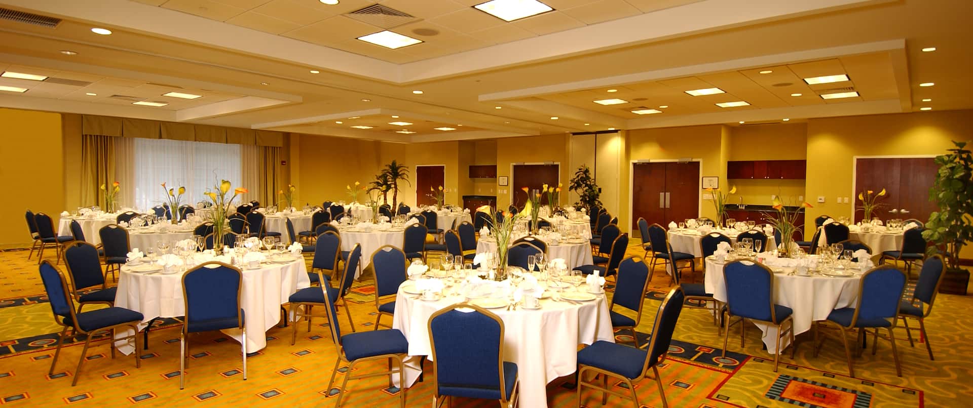 Place Settings and White Linens on Round Tables With Blue Chairs in Birch Cedar Room Set Up for Banquet