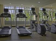 Fitness center with equipment facing a wall of windows with a city view