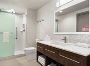 Spacious guest bathroom featuring stand up shower with frosted glass doors, vanity, and mirror.