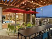 Outdoor patio next to indoor pool featuring ample seating, BBQ grills, and beautiful mountain view.