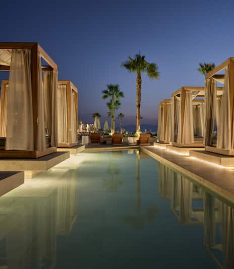 Cabanas in Outdoor Pool Area with Palm Trees at Night