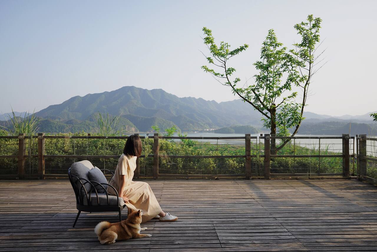 Woman with dog looking out over lake from deck
