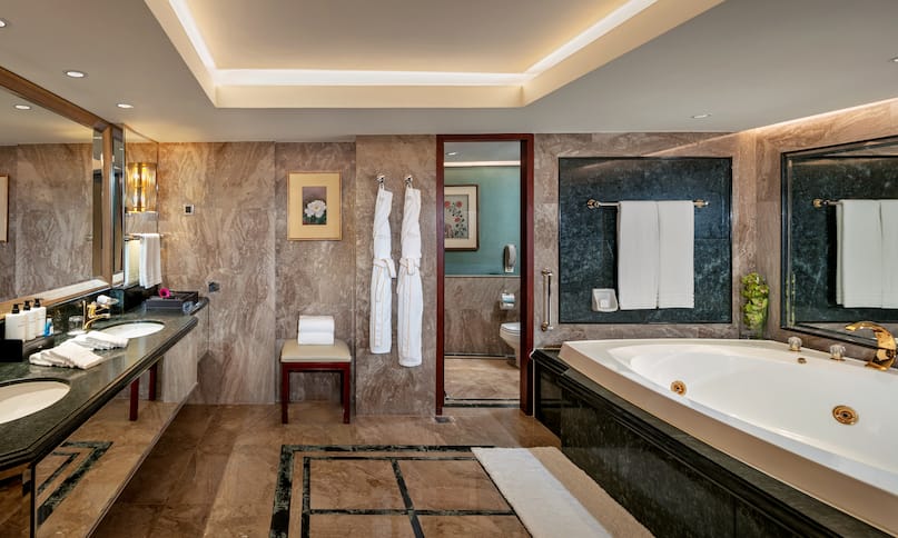 Dual Vanity Area with Amenities and a Bathtub in a Suite-previous-transition
