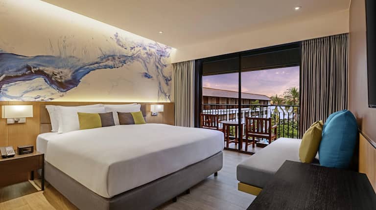 Large Bed and Sofa in a Guest Room with Balcony at Sunset