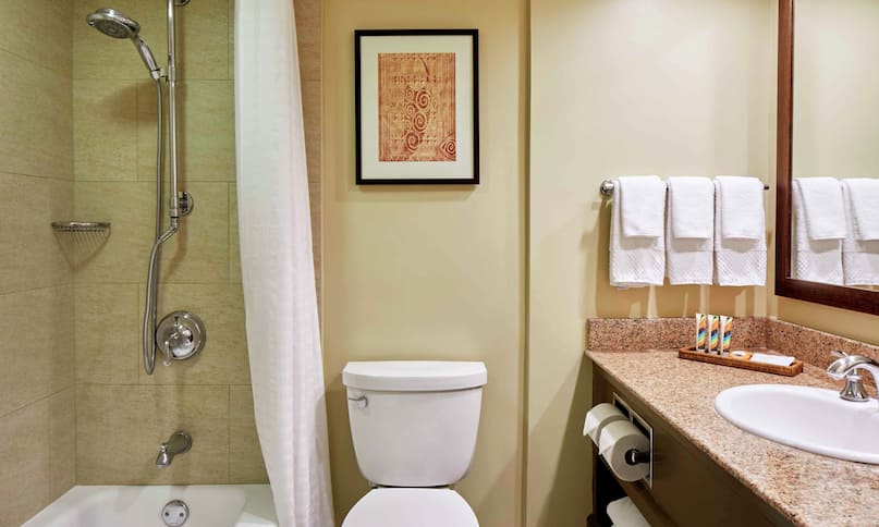Salle de bain d'une chambre dans la tour Diamond Head avec vue sur le complexe, toilettes, miroir, comptoir lavabo, douche et baignoire, transition précédente