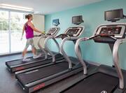Woman on One of Three Fitness Center Treadmill by Large Windows
