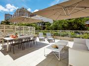 Sofas, Tables With Sun Umbrellas, and Loungers on Outdoor Patio of Large Lanai Suite on Sunny Day