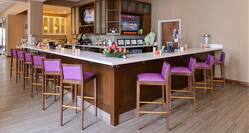 Fully Stocked Bar With Purple Bar Chairs at an Angle