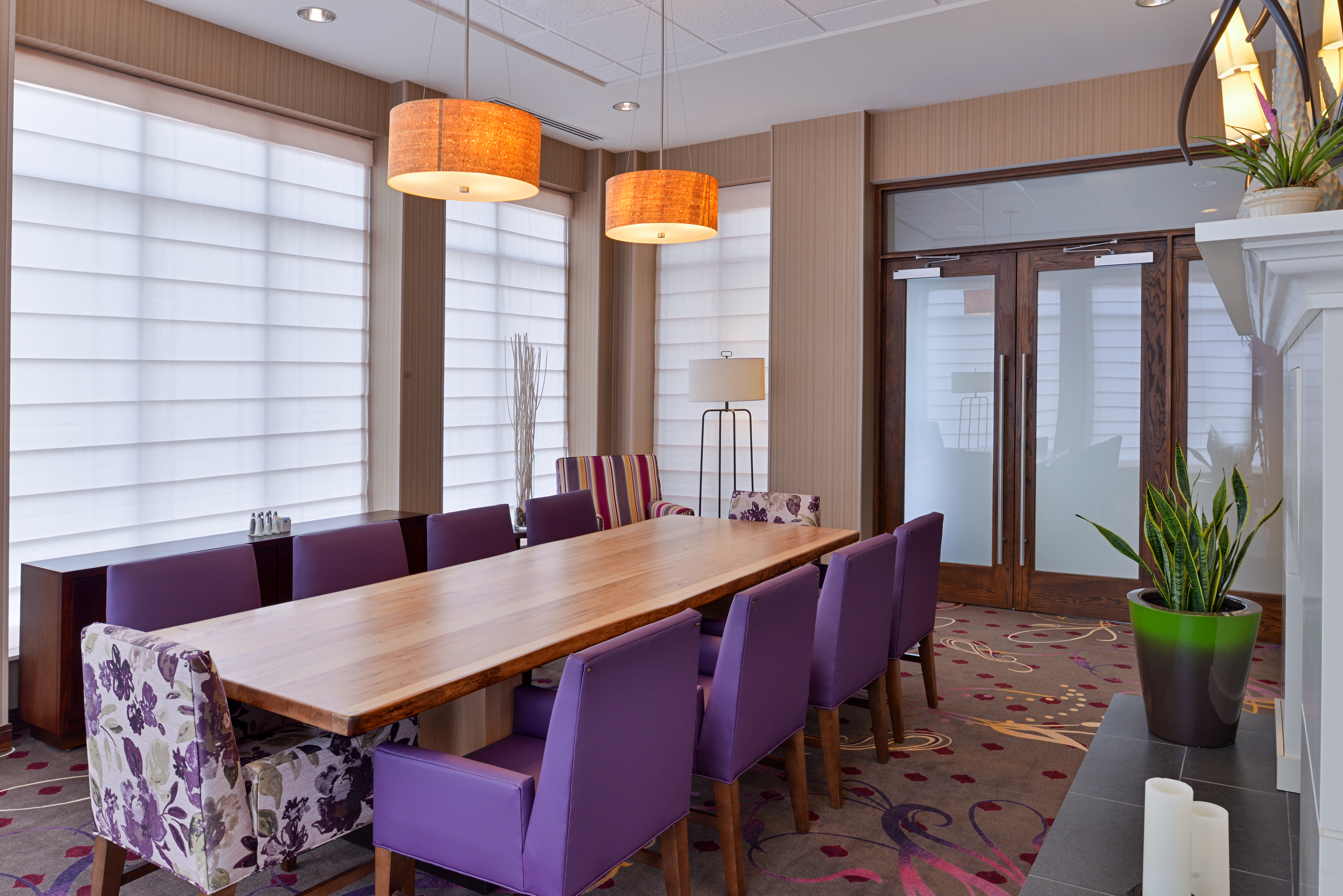 Conference Room With Large Windows and Long Table Surrounded by Purple Chairs