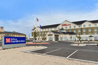 Daytime View of Hotel Exterior, Signage, Flagpoles, Landscaping, Circle Driveway, and Parking Lot