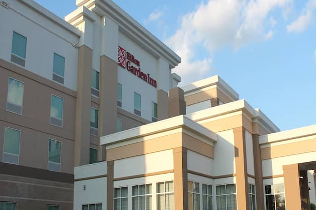 Angled View of Hotel Exterior, Signage, and Landscaping in Daytime