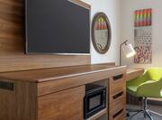 Convenient guest room work desk with ergonomic chair, TV, and mini-fridge.