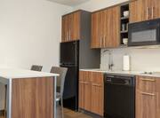 Bright kitchen area in junior suite equipped with breakfast bar, full size refrigerator, dishwasher, and cook top stove..