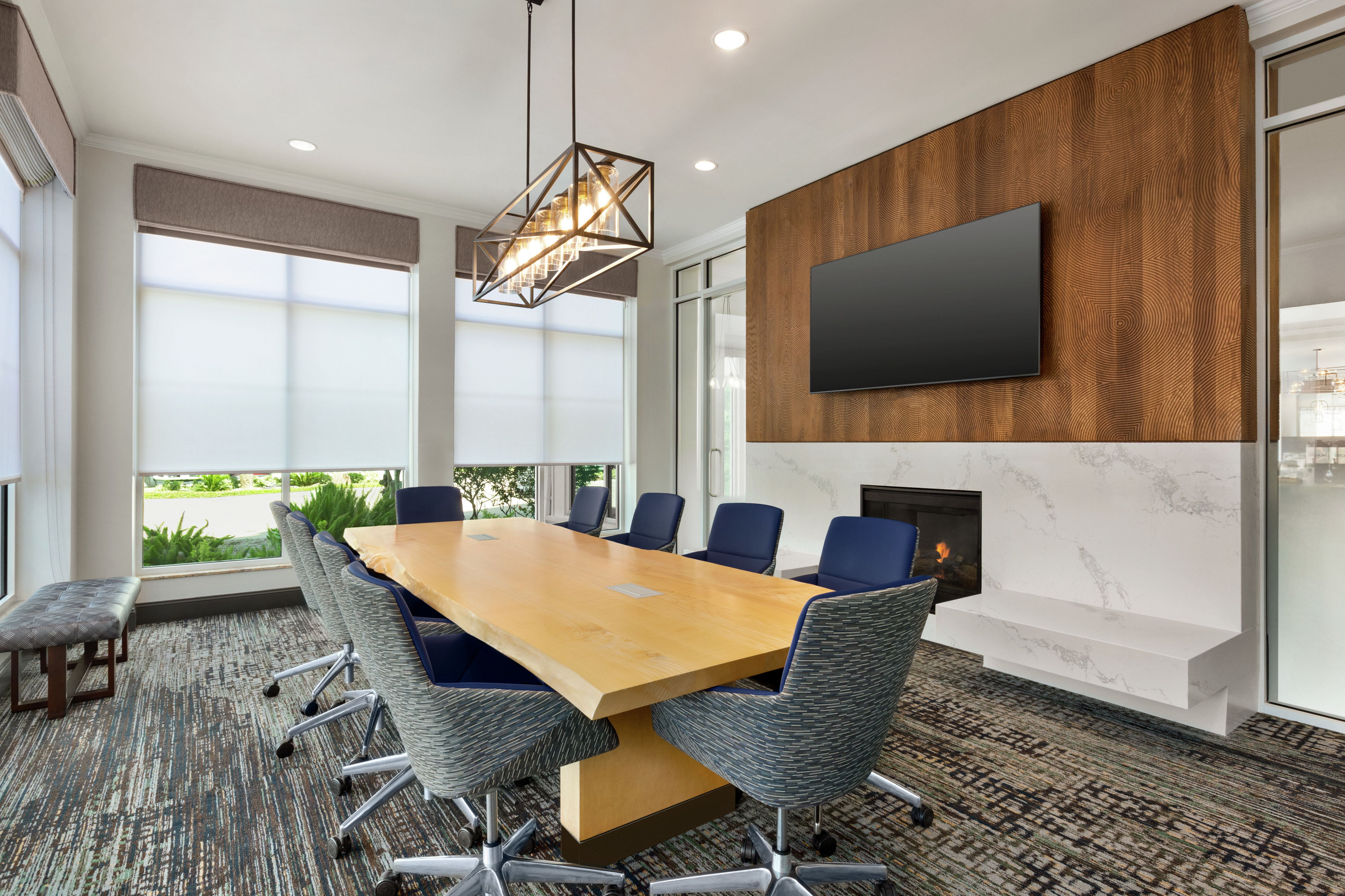 Spacious meeting room with large boardroom table, fireplace, and TV.