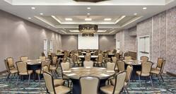 Spacious on-site ballroom fully set with banquet round tables and project screen at front of room.