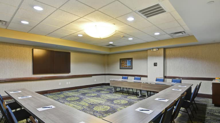 Sala de reuniones Sage en forma de U con mesa, sillas y televisor