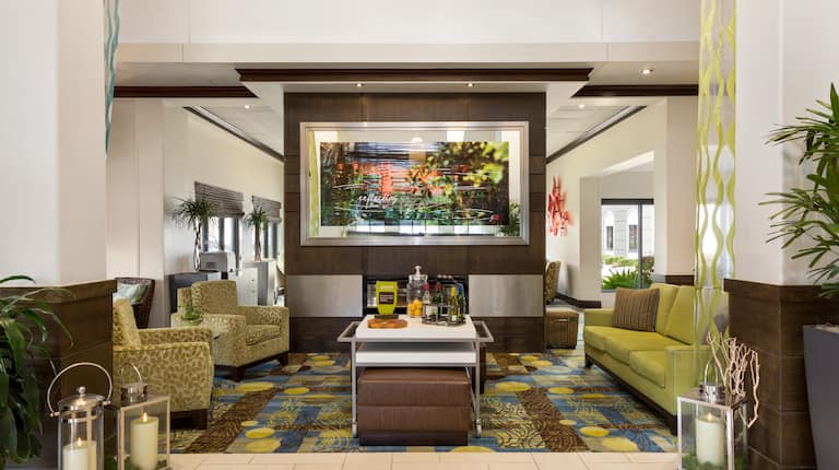 Lobby Hospitality Lounge Area By Fireplace With Art Feature, Soft Seating, and Beverage Station