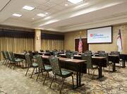 Classroom Style Meeting Room With Tables and Chairs Facing Presentation Screen  Between American and Texan Flags