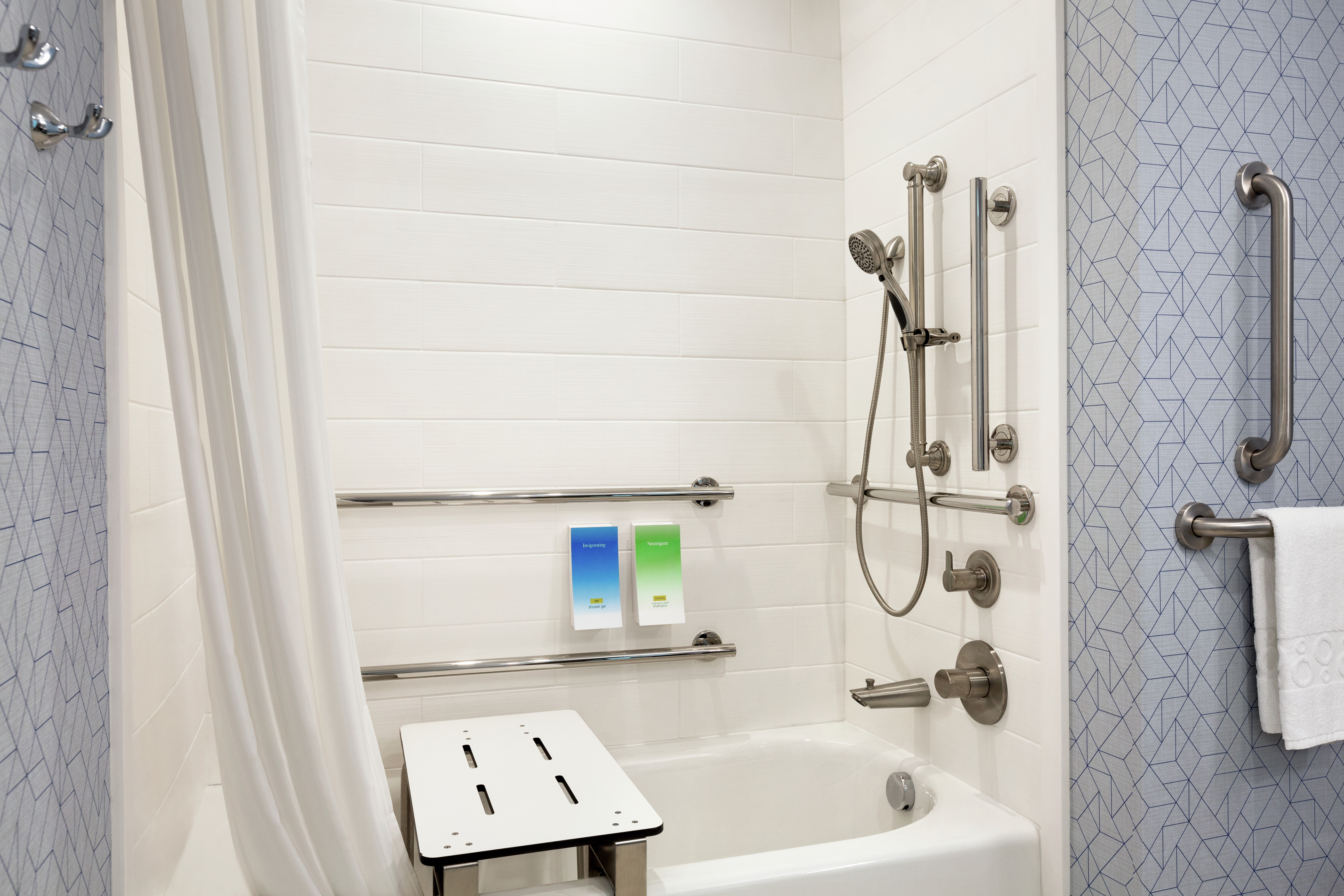 Accessible tub with seat, mobile shower head, and dispensable bathroom amenities.