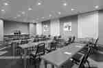 Spacious meeting room with classroom style tables, chairs, notepads, pens, and refreshment station.
