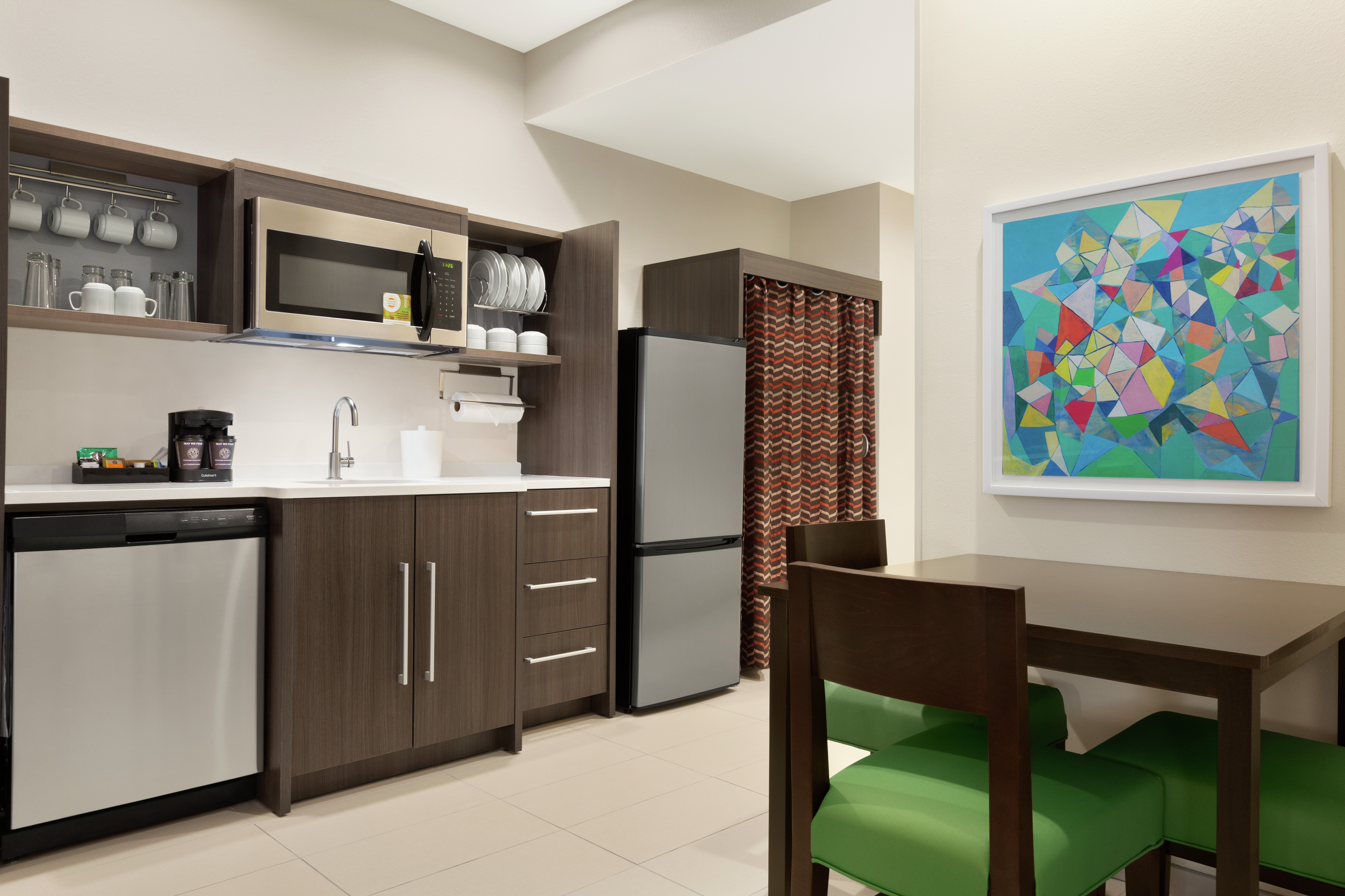 Spacious suite featuring dining table, abstract framed art on wall, and fully equipped kitchen.