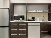 Fully equipped accessible kitchen in studio suite featuring fridge, microwave, dishwasher, and coffee maker.