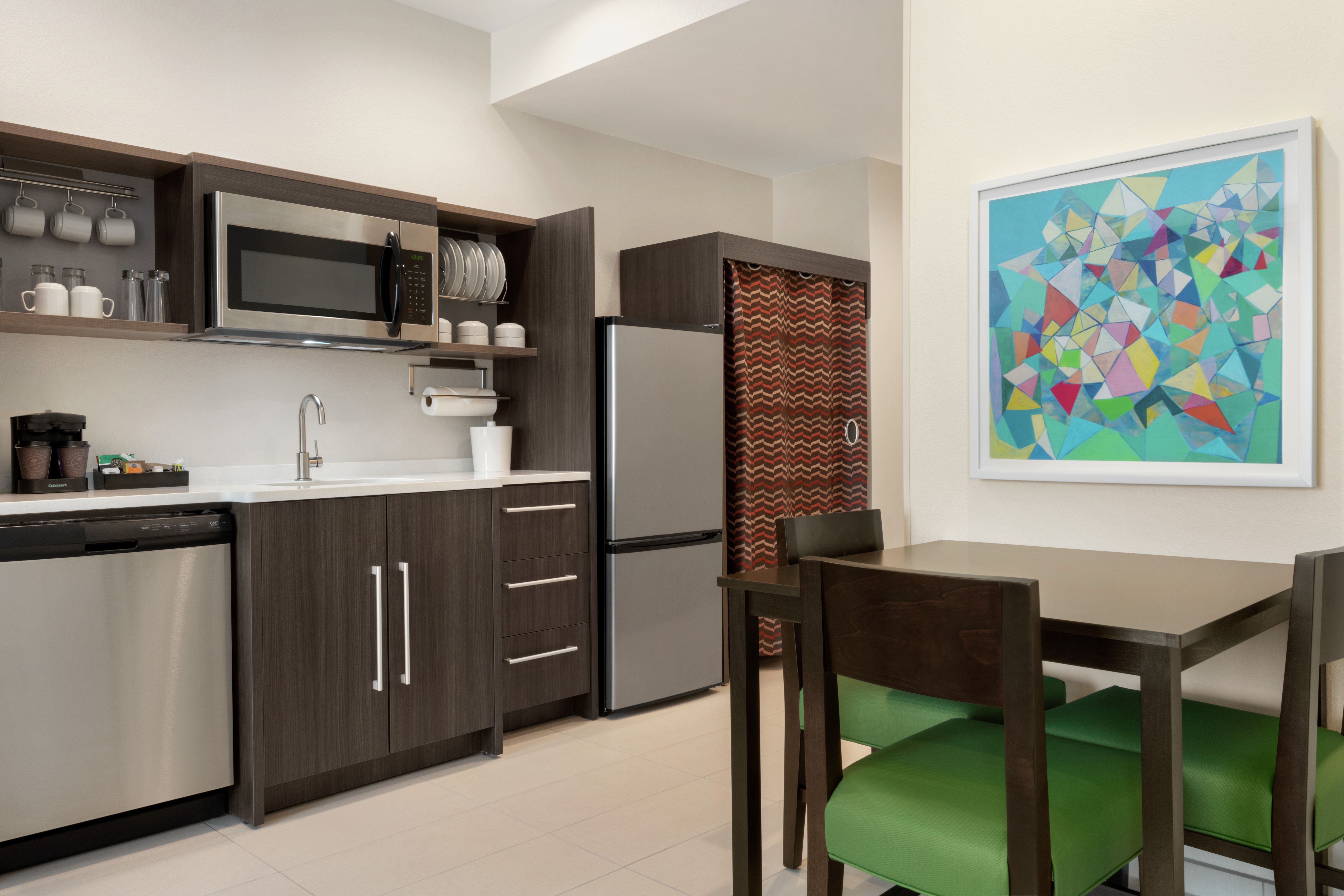 Spacious kitchen in suite featuring dining table, fridge, dishwasher, and microwave.