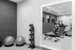 Spacious fitness center featuring cardio machines, medicines balls, and full length mirror.