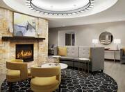 Spacious lobby space featuring stylish design, fireplace with abstract art above, seating area, and large circular ceiling light fixture.