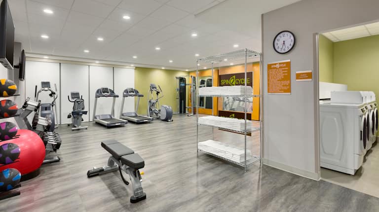 Fitness Center with Weight Bench, Treadmills, Cycle Machine and Cross-trainer with View of Guest Laundry Room