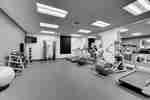 Fitness Center With Green Exercise Ball, Free Weights, TV Above Weight Balls, Weight Machine With Bench, and Cardio Equipment Facing Two Large Mirrors