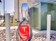 Detailed View of Tesla Charging Station With Red Electric Vehicle Parking Sign