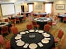 Round Dining Tables With Place Settings on Black Linens, Presentation Screen and Windows With Long Drapes in Venitian Ballroom