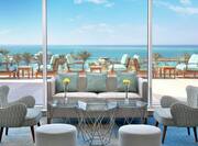 Coquina Lobby Bar Indoor Seating with a Variety of Seating Options and Floor to Ceiling View of Balcony with a Backdrop of the Red Sea