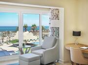 Hotel Guest Suite with Chair Positioned by Wall of Windows and a Breathtaking View of the Beach and the Red Sea