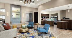 Stylish lobby featuring comfortable seating area, metallic art piece chandelier, front desk, and snack shop.