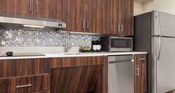 Spacious accessible kitchen in suite featuring fridge, dishwasher, microwave, coffee maker, and cook top stove.