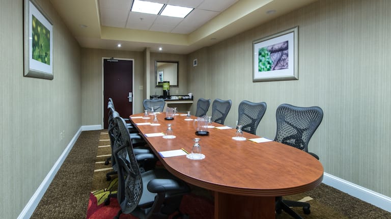 Oval Boardroom Table With Wall Art Seating for Nine and Refreshment Station by Entry