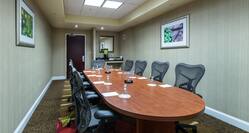 Oval Boardroom Table With Wall Art Seating for Nine and Refreshment Station by Entry