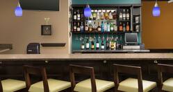 Chairs Angled at Fully Stocked Lobby Bar With TV