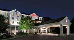  Angled View of Hotel Exterior, Signage, Flagpoles, Landscaping, and Circle Driveway Illuminated at Night