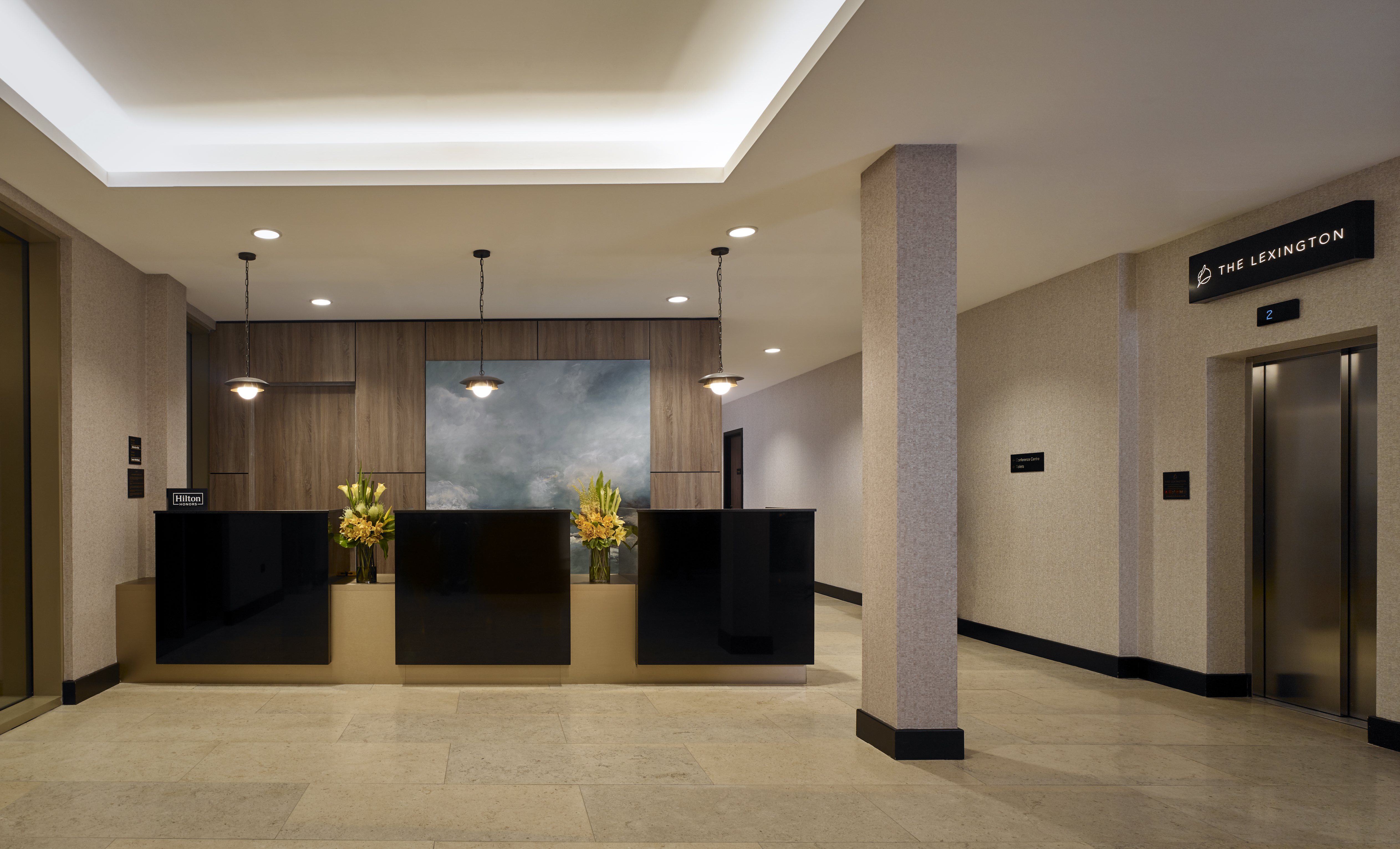 Hotel Front Desk Reception Area with Modern Brown and Tan Decor and Fresh Flowers with Granite Floor and Grand Ceiling
